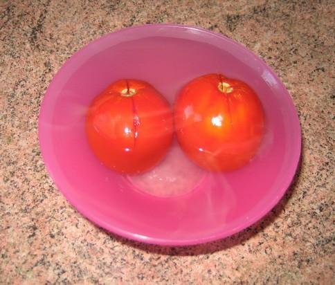Моем помидоры, делаем сверху неглубокий надрез крест-накрест, складываем их в мисочку и заливаем кипятком так, чтобы вода покрыла овощи